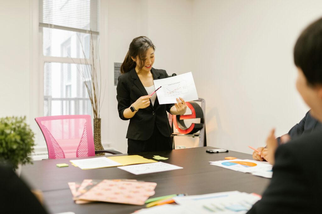 An English language tutoring student stands in an office giving a presentation.
